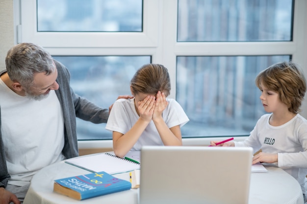 Problem. Das Mädchen schließt ihr Gesicht und sieht aufgebracht aus, während der Vater versucht, sie zu beruhigen