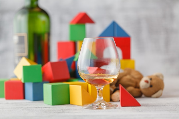 Problema de alcoholismo. Ciudad de bloques de juguete roto, ladrillos de construcción de casas para bebés, niños cúbicos de madera sobre pared blanca