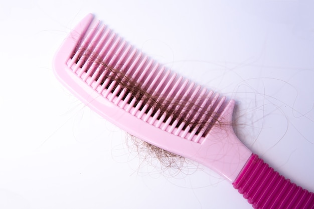 Problema de caída del cabello. Peine rosa sobre fondo blanco.