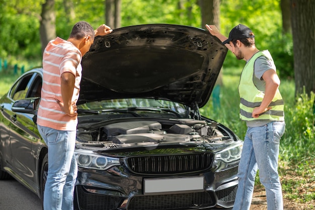 problema del coche Un conductor discutiendo un accidente automovilístico con un hombre de servicio y luciendo inseguro