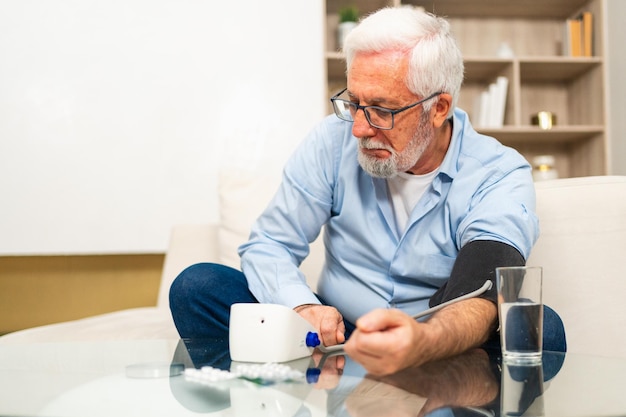 Problema de hipertensão em idosos homem idoso medindo a pressão arterial com tonometro em casa idoso