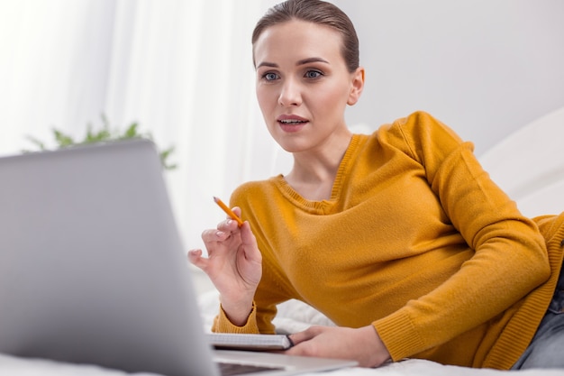 Problema laboral. Freelancer mujer pensativa profesional abriendo la boca mientras trabaja en casa y lápiz de levantamiento