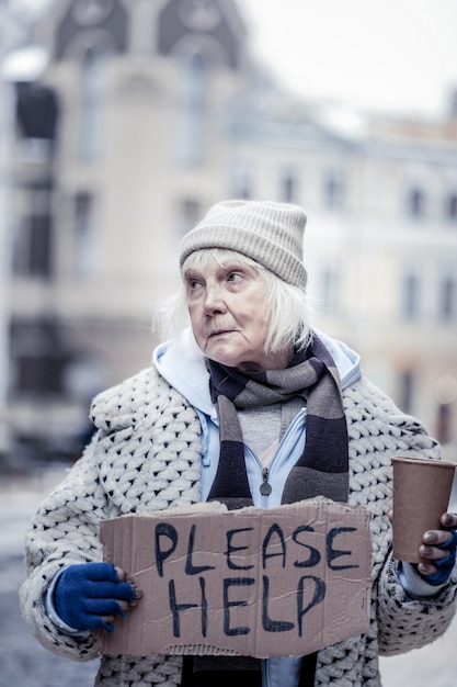 Problema social. Mujer mayor deprimida pidiendo limosna en la calle sin tener dinero para vivir