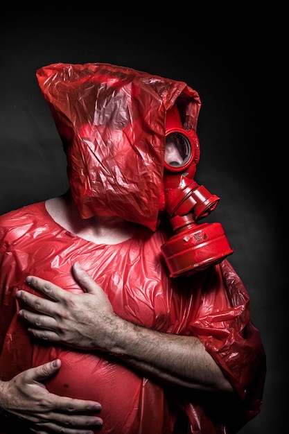 Foto problema, um homem com uma máscara de gás sobre a fumaça. fundo preto e cores vermelhas