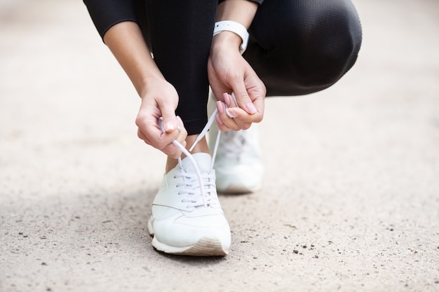 Problema de las zapatillas de deporte. Corredor femenino atar sus zapatos preparándose para correr