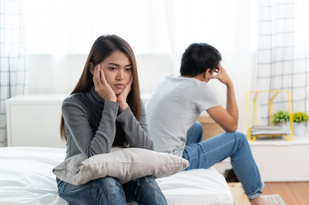 Foto problemas de relacionamento de casal de amantes. triste jovem esposa sentada na cama de costas para o marido após discussão.