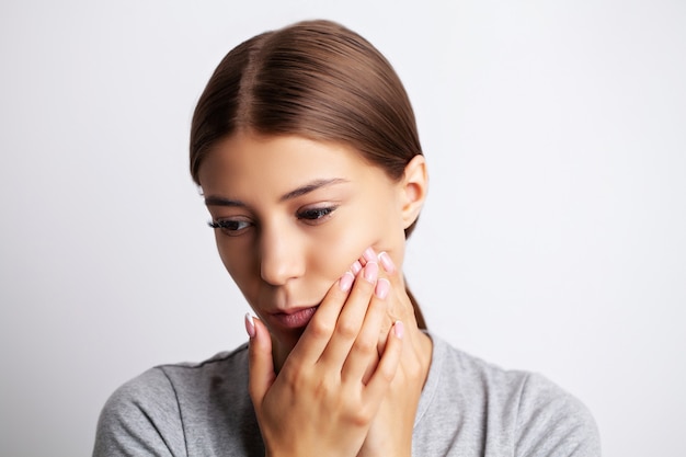 Problemas dentales, una mujer atractiva está experimentando un doloroso dolor de muelas.