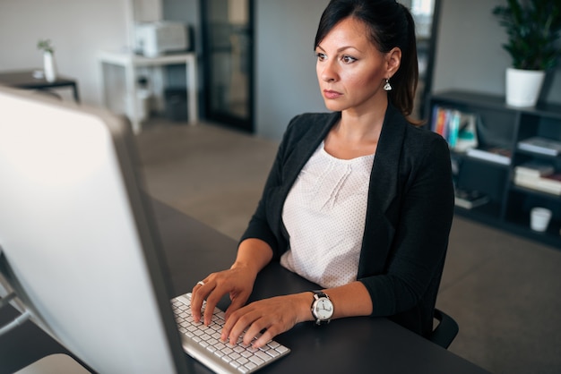 Problemas en la empresa. Grave empresaria escribiendo en el teclado.