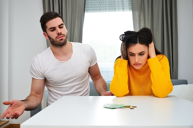 Foto problemas matrimoniales, problemas de dinero, manejo responsable del dinero, concepto de ahorro. pareja joven mirando dinero sobre la mesa, mirando preocupado.