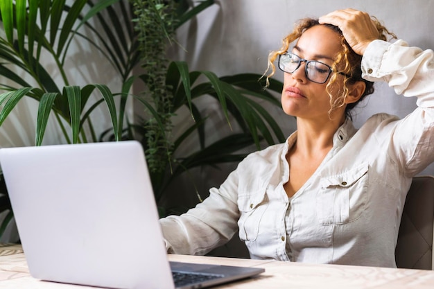 Problemas para trabalhar no trabalho on-line do laptop Uma mulher tocando a cabeça, sofrendo de enxaqueca, notificação de dia ruim Empresária feminina, problemas em pequenas empresas Pessoas que trabalham no computador cansadas