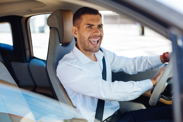 Problemas de trafico. Buen hombre emocional dando una señal mientras conduce un coche