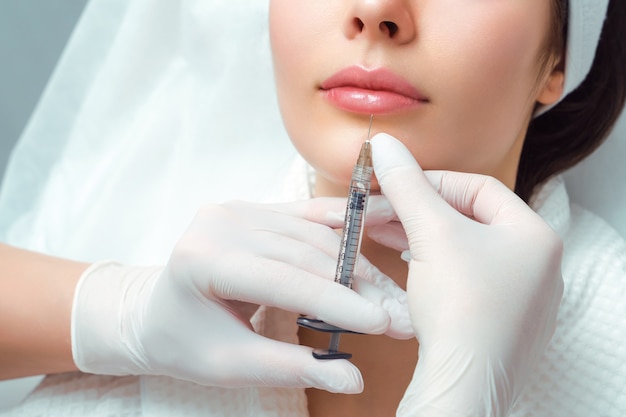 Foto procedimento de correção da forma labial em um salão de cosmetologia. o especialista faz uma injeção nos lábios do paciente. aumento de lábios.