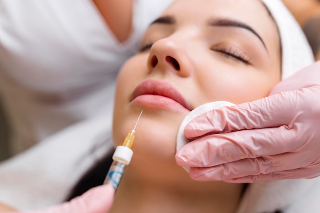 Procedimento de correção da forma labial em um salão de cosmetologia O especialista faz uma injeção nos lábios do paciente Aumento labial