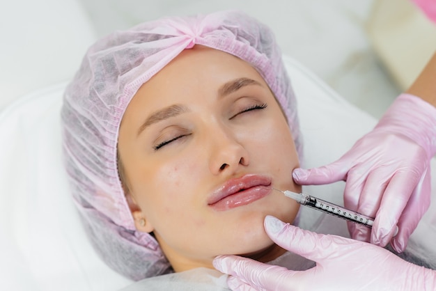 Procedimento de cosmetologia para aumento dos lábios e remoção de rugas em uma linda jovem. cosmetologia.