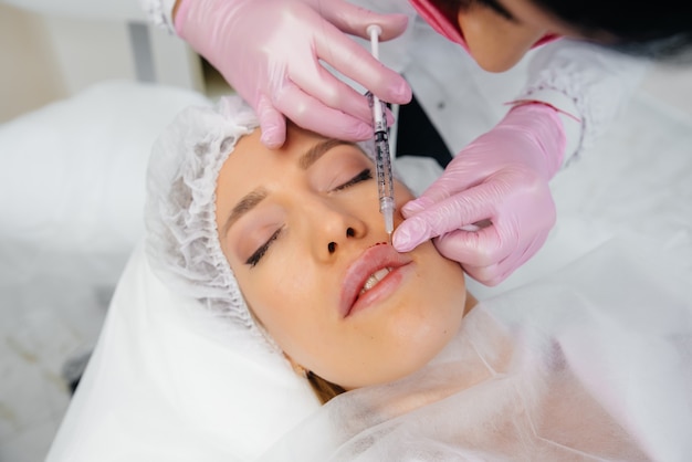 Procedimento de cosmetologia para aumento dos lábios e remoção de rugas para uma jovem
