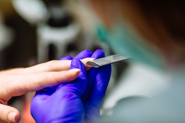 Procedimento de cuidados de manicure, mulher em um salão de beleza recebendo uma manicure por uma esteticista