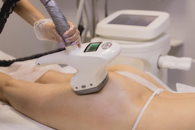 Procedimento de elevação de RF de massagem anticelulite de hardware A esteticista orienta o dispositivo ao longo da nádega