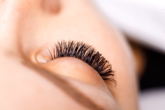 Procedimento de extensão de cílios. Olho de mulher com cílios longos. Cílios, close-up.