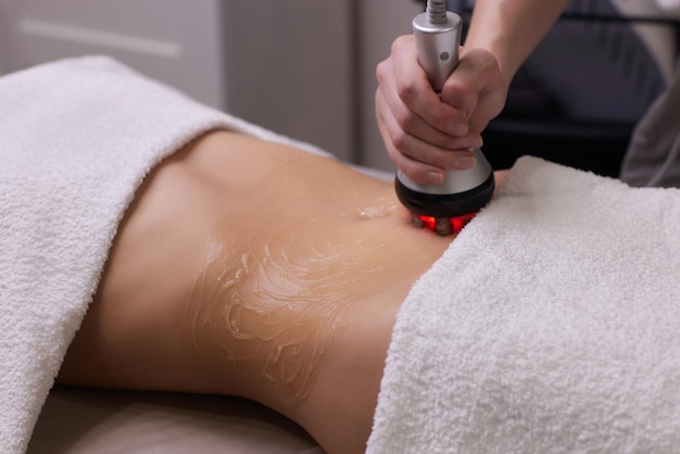 Foto procedimento de remoção de celulite no abdômen feminino, massagem na barriga de cavitação. massagem ultrassônica para perda de peso. correção da figura feminina sem intervenção cirúrgica. close da barriga.