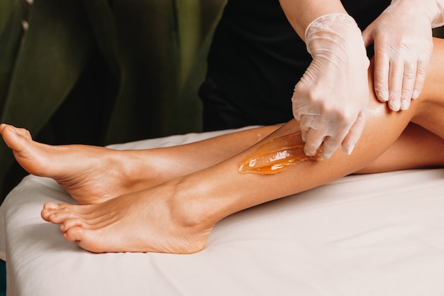 procedimiento de azúcar realizado en el salón durante una sesión de protección de la piel de las piernas