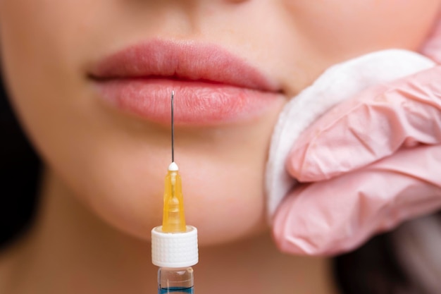 Procedimiento de corrección de forma de labios en un salón de cosmetología El especialista hace una inyección en los labios del paciente Aumento de labios