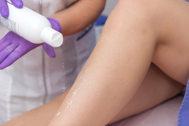 Procedimiento cosmético aplicando talco en las piernas depilación depilación frotando talco suavizante de la piel