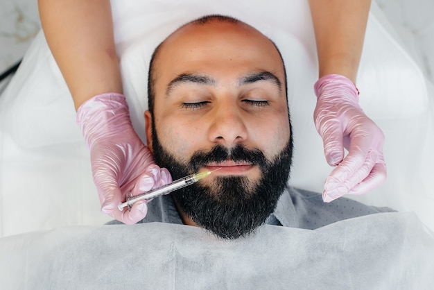 Procedimiento cosmético para el aumento de labios en un hombre barbudo.