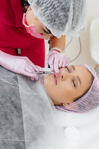 Procedimiento de cosmetología para el aumento de labios y la eliminación de arrugas de una hermosa joven. Cosmetología.