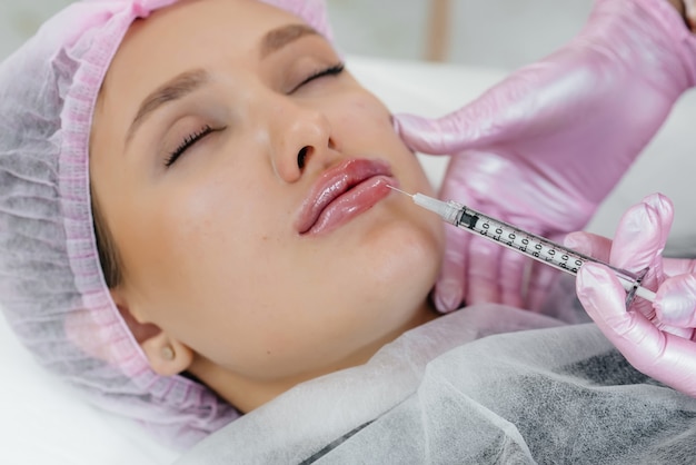 Procedimiento de cosmetología para el aumento de labios y la eliminación de arrugas para una joven hermosa