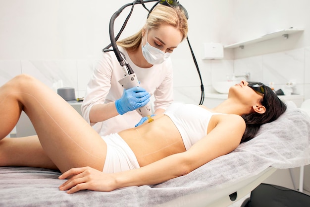 Procedimiento de depilación con láser de alejandrita en la clínica de cosmetología cosmetólogo médico en uniforme