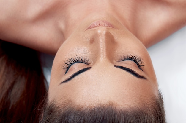 Procedimiento de extensión de pestañas. Hermosa mujer con largas pestañas en un salón de belleza