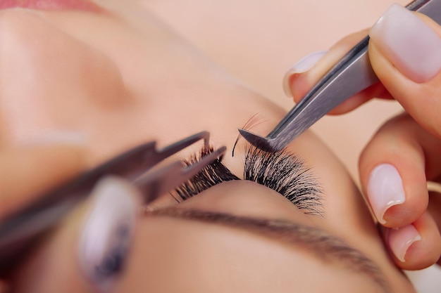 Foto procedimiento de extensión de pestañas ojo de mujer con largas pestañas azules efecto ombre de cerca el enfoque selectivo