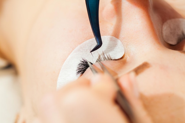 Procedimiento de extensión de pestañas. Ojo de mujer con pestañas largas. Pestañas de cerca, vista macro y enfoque selectivo.