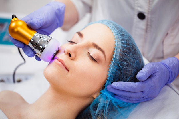 Foto el procedimiento de fotodepilación en el salón de belleza. una mujer joven se quita el vello no deseado en la cara. cosmetología de hardware. terapia de microcorriente. de cerca