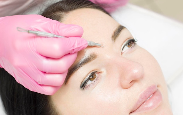 Procedimiento para limpiar la piel con herramienta de acero de espinillas y acné Limpieza profunda del rostro femenino con removedor de espinillas en el salón de belleza Cosmetólogo que recibe terapia de limpieza