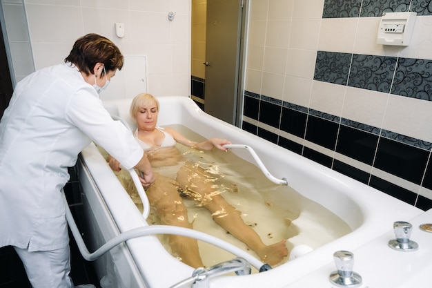 El procedimiento de masaje de ducha bajo el agua en el baño. Chica sobre el procedimiento de masaje bajo el agua.