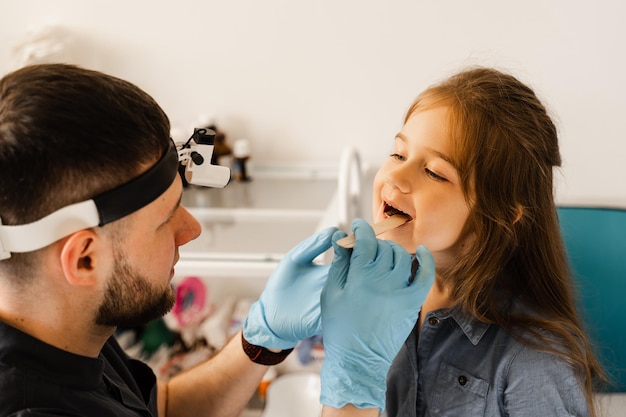 Procedimiento de orofaringoscopia El otorrinolaringólogo examina la garganta del niño con una espátula Consulta con el laringólogo