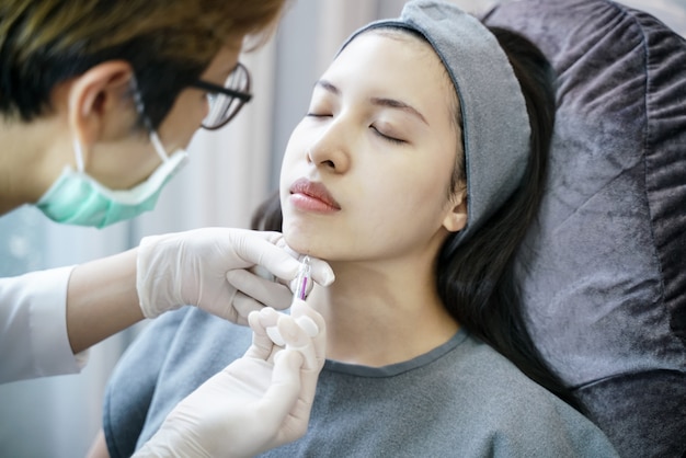 Procedimiento de rejuvenecimiento en inyección de belleza clínica. Inyección de mujer en la barbilla.