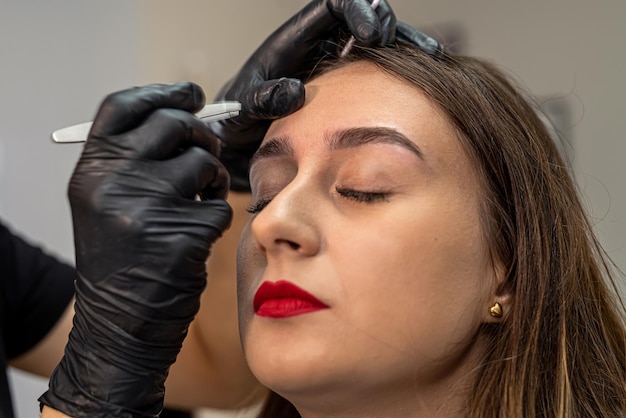 Procedimiento de un salón de belleza para pintar cejas con pincel tinte de cejas para cliente con lashmaker