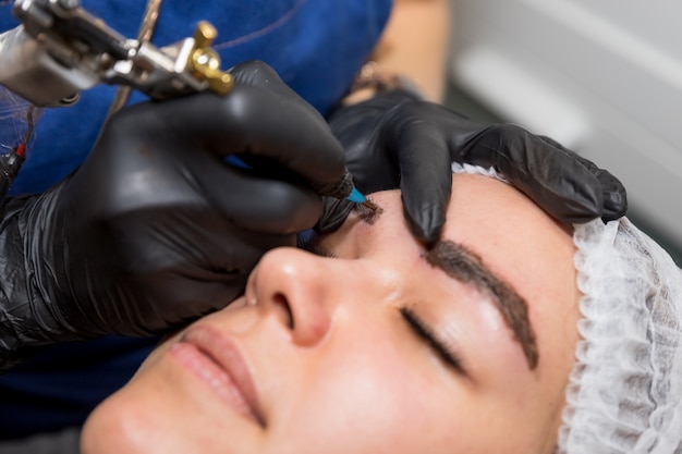Foto procedimientos cosméticos para el tratamiento de cejas. microblading en el salón de belleza. cosmetología profesional. el proceso de aplicar el pigmento, dar forma a las cejas, cejas de maquillaje permanente, tatuajes