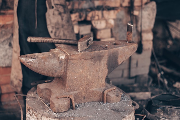 Foto procesar metal con martillo sobre yunque en fragua golpear hierro al aire libre en taller con fuego herrería metalúrgica