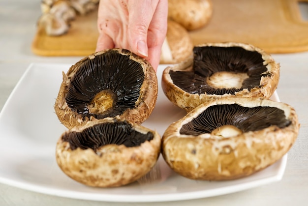 Proceso de cocción de champiñones Portobello crudo en el plato Proceso de cocción de champiñones portobello rellenos Comida vegetariana de cerca