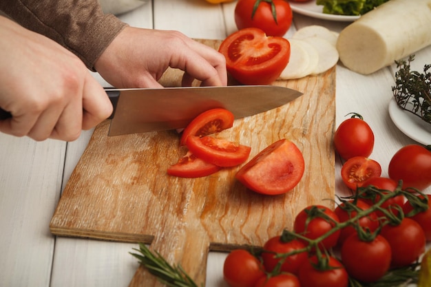 Proceso de cocción del gazpacho, sopa fría tradicional española hecha con verduras frescas. Mano de mujer cortando tomates frescos, vista superior