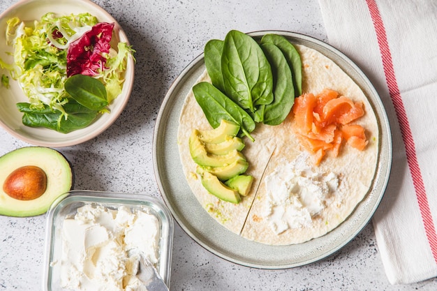 Foto proceso de cocción del sándwich e ingredientes proceso de preparación de quesadilla con aguacate, salmón, requesón y espinacas trendy wrap hack paso a paso paso 1