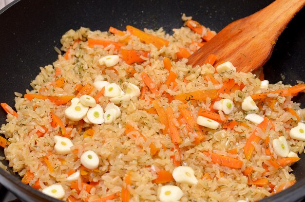 El proceso de cocinar arroz con verduras en chino en una sartén.