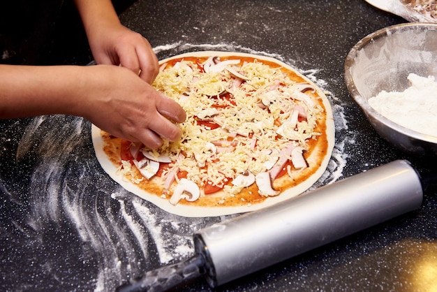 Foto el proceso de cocinar pizza con carne, champiñones, tomates y queso.