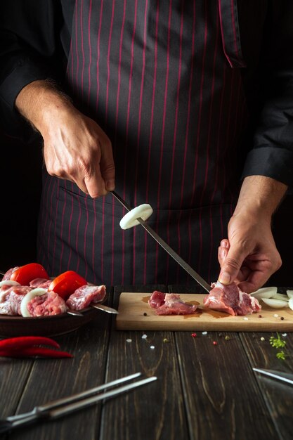 El proceso de cocinar shish kebab de carne de ternera cruda en la cocina con las manos de un chef