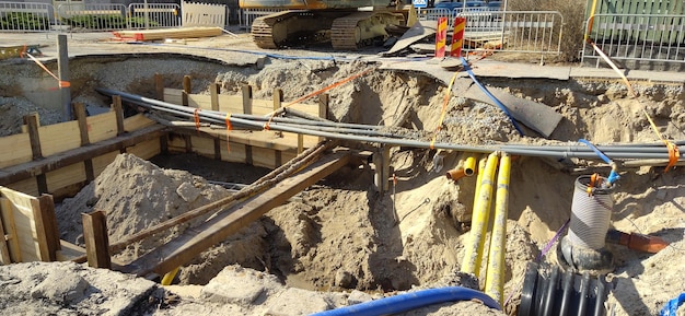 El proceso de colocación de sistemas de ingeniería y calefacción. Muchas tuberías de plástico multicolores se encuentran en una zanja de arena en perspectiva.