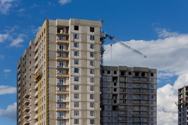 Proceso de construcción de un gran edificio de apartamentos residenciales con grúa sobre fondo de cielo nublado