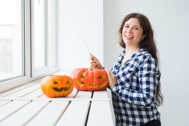 Proceso de corte de calabaza de Halloween. Mujer joven haciendo Jack-o-lantern.